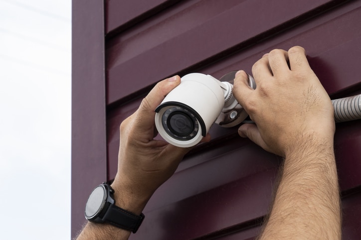 a video surveillance camera in the hands of a technician. installation of outdoor video surveillance in close up. technician installing cctv camera on wall outdoors, closeup